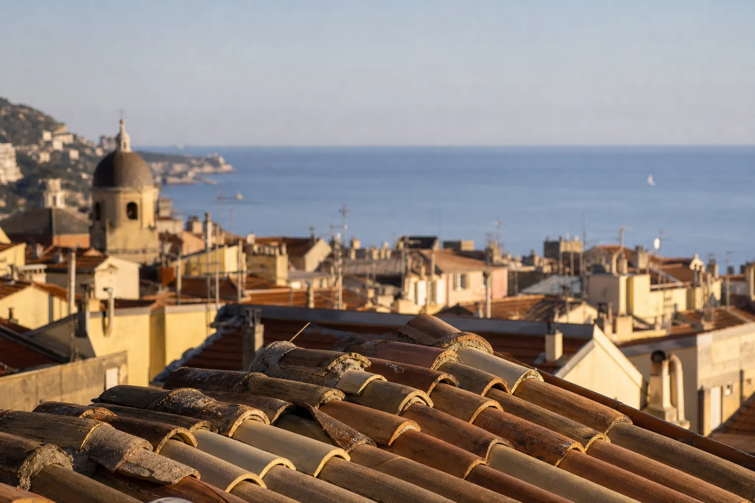 Toits de tuiles romaines du Vieux-Nice et mer en arrière-plan, en fin de journée
